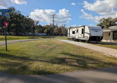 Camper on a grassy lot with concrete pad and driveway