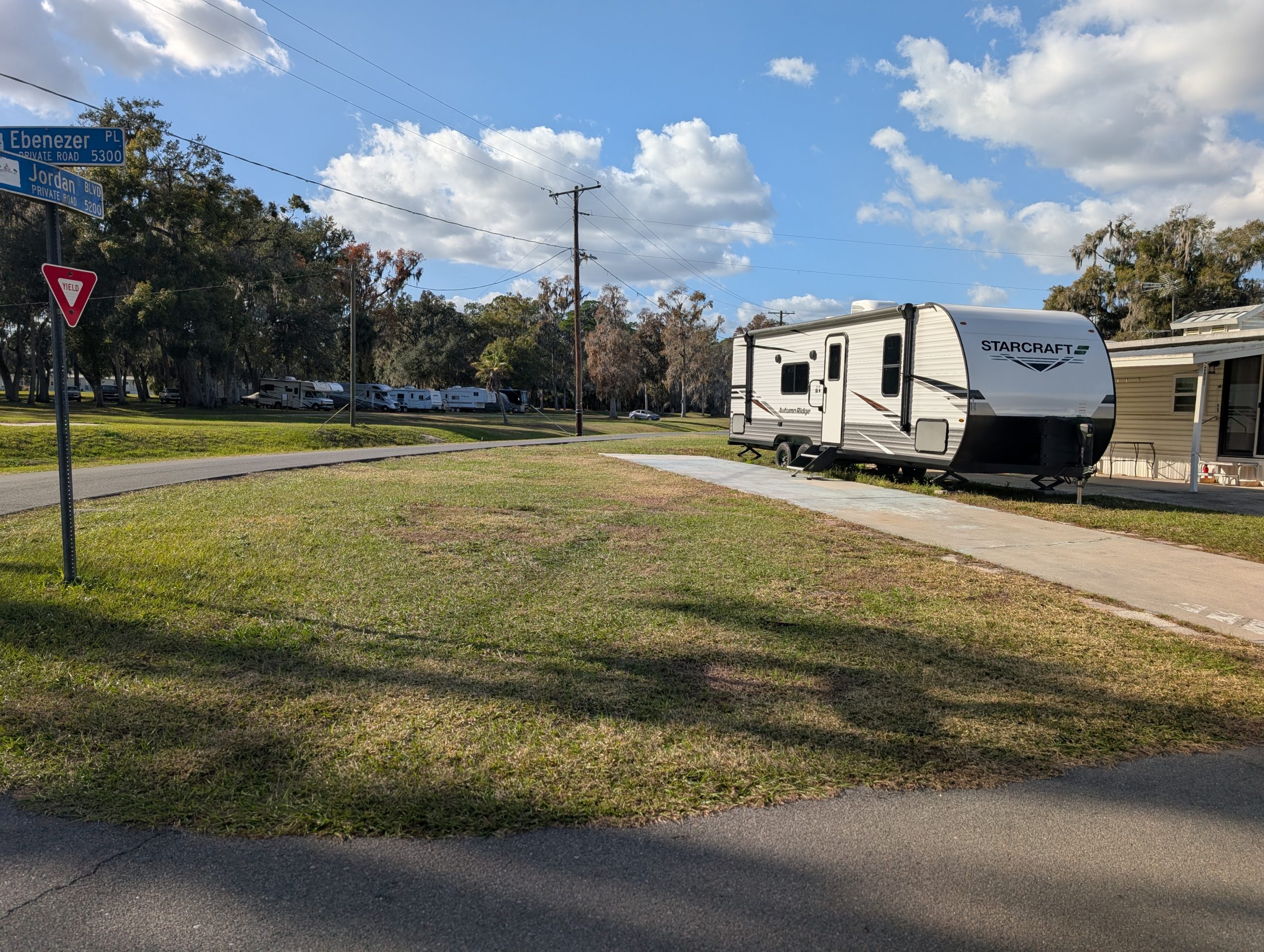 Camper on a grassy lot with concrete pad and driveway